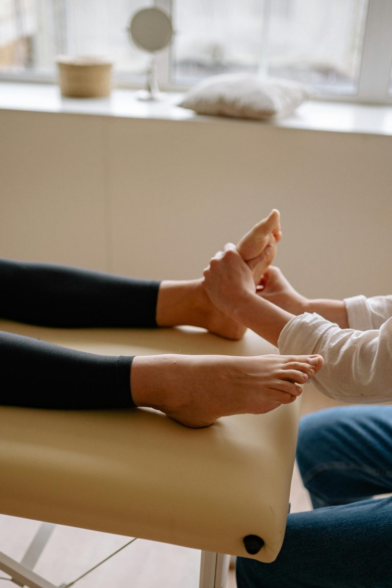 A professional massage therapist providing foot reflexology on a comfortable massage table.